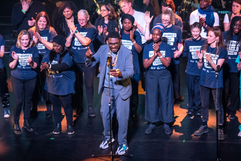 Kwame Kwei-Armah, St George's Staff Choir and ONHS Live performers on stage clapping and smiling