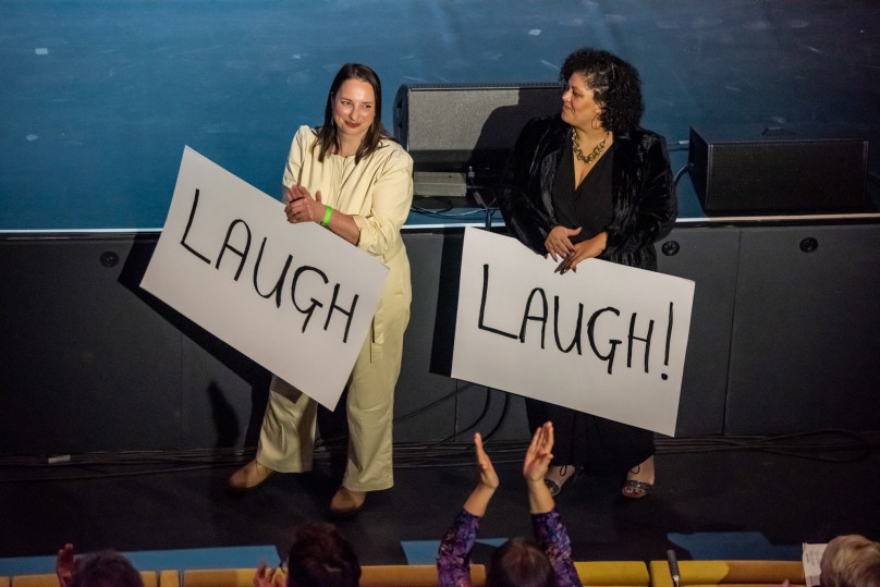 Two people holding up signs saying Laugh and smiling at each other